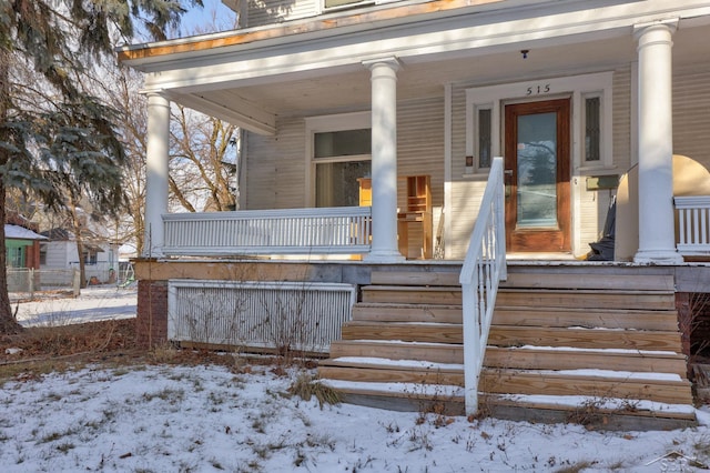 snow covered property entrance featuring covered porch