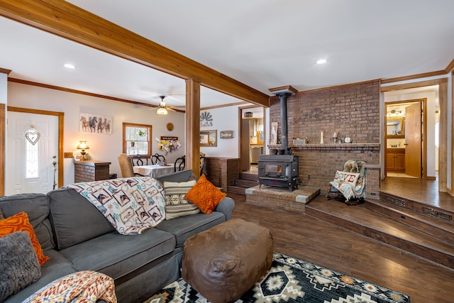 living room featuring crown molding, hardwood / wood-style flooring, ceiling fan, beamed ceiling, and a wood stove