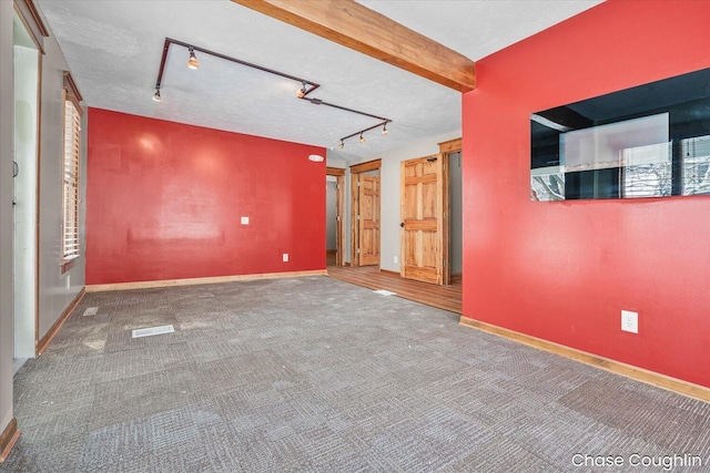 carpeted spare room with track lighting, beamed ceiling, and a textured ceiling