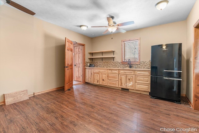 kitchen featuring a textured ceiling, dark wood-type flooring, black refrigerator, sink, and backsplash