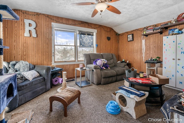 carpeted living room featuring ceiling fan, a textured ceiling, wooden walls, and lofted ceiling