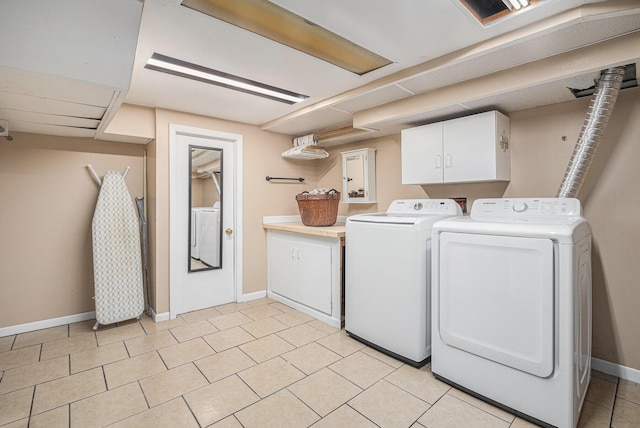 clothes washing area with cabinets, washing machine and dryer, and light tile patterned flooring