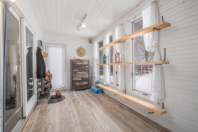 interior space featuring track lighting, wood-type flooring, and wood walls