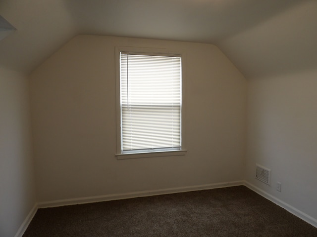 bonus room with dark carpet and lofted ceiling