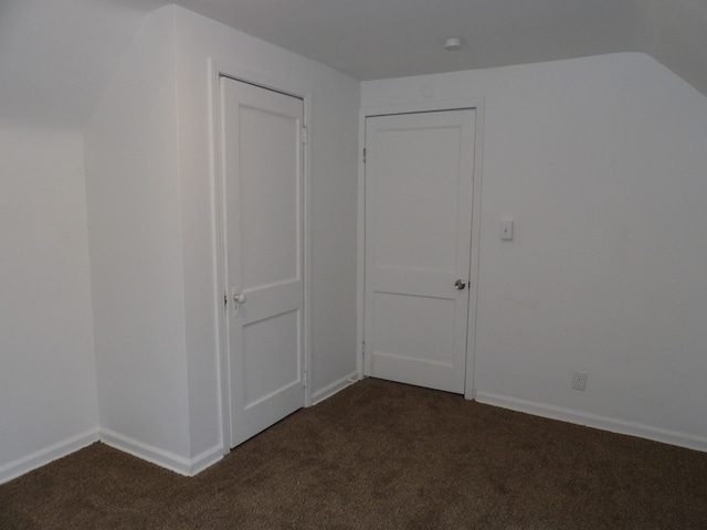 additional living space featuring vaulted ceiling and dark colored carpet