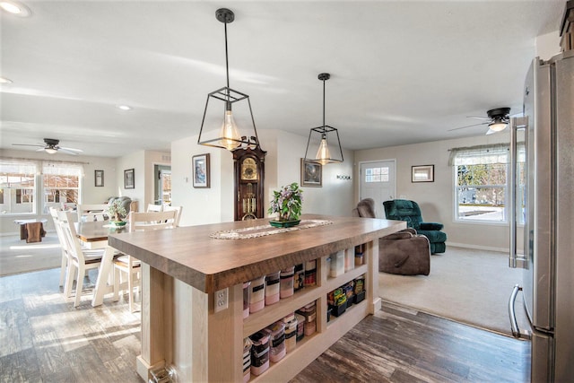 kitchen with a center island, wood-type flooring, high end fridge, hanging light fixtures, and ceiling fan