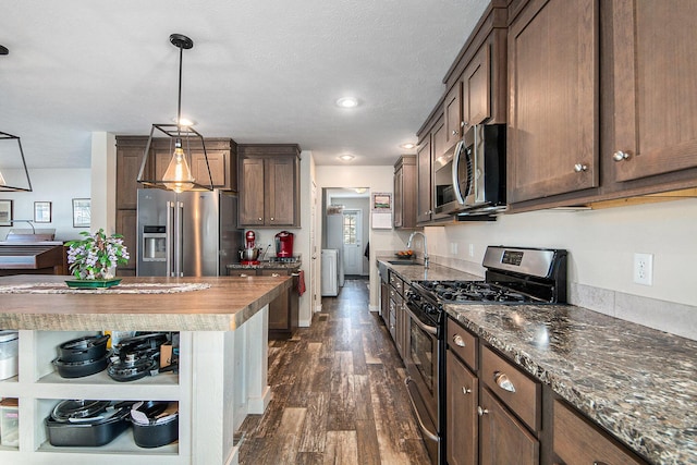 kitchen featuring pendant lighting, wooden counters, sink, dark hardwood / wood-style flooring, and appliances with stainless steel finishes