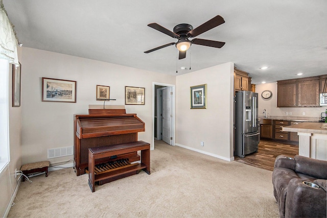 living room with light carpet, sink, and ceiling fan