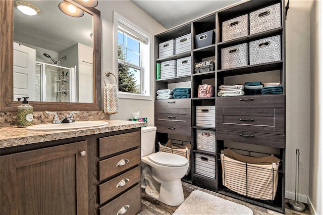 bathroom featuring hardwood / wood-style flooring, a shower with door, toilet, and vanity