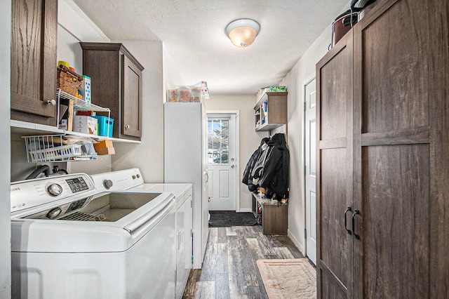 washroom with cabinets, a textured ceiling, washer and clothes dryer, and dark hardwood / wood-style floors