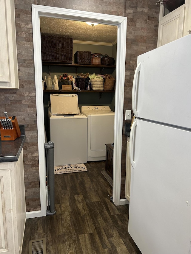 washroom with crown molding, independent washer and dryer, and dark hardwood / wood-style floors