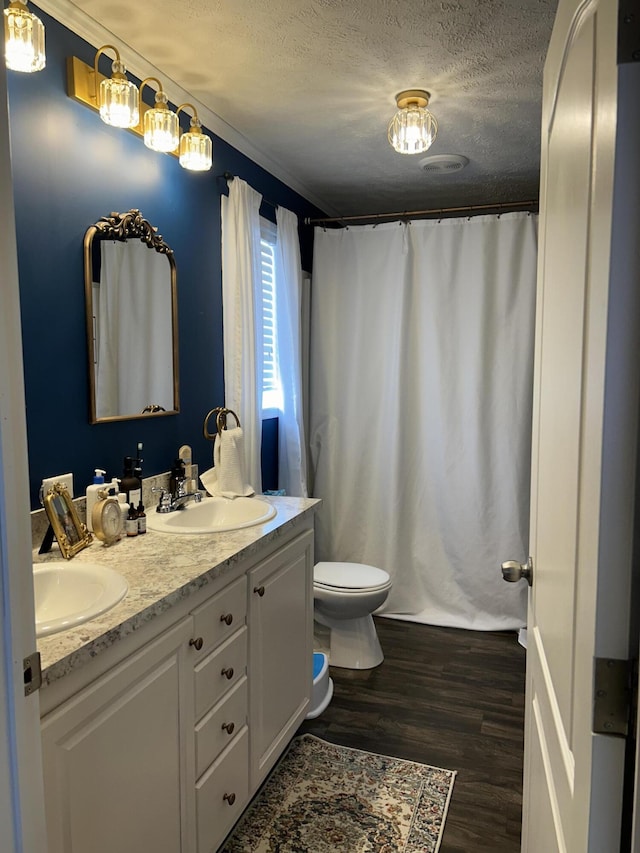 bathroom with toilet, crown molding, a textured ceiling, hardwood / wood-style flooring, and vanity