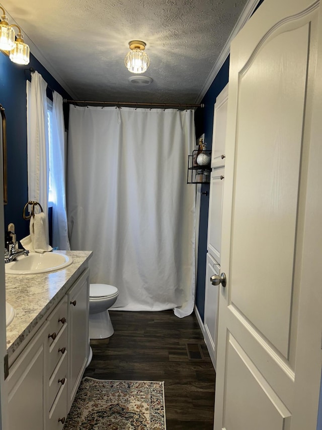 bathroom with wood-type flooring, a textured ceiling, toilet, vanity, and ornamental molding