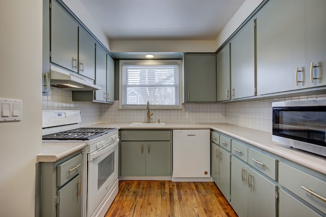 kitchen featuring sink, white appliances, light hardwood / wood-style floors, and decorative backsplash