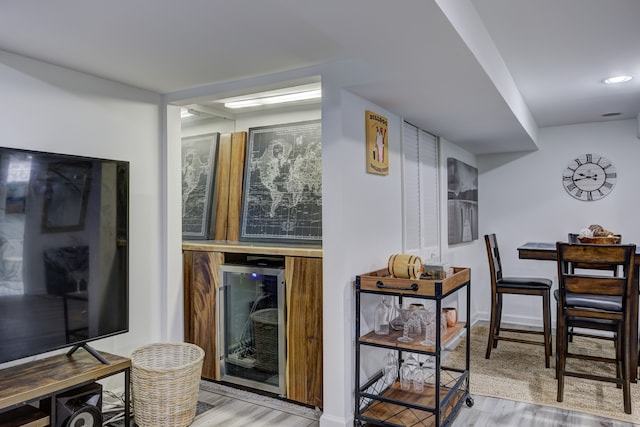 bar with beverage cooler and light hardwood / wood-style floors