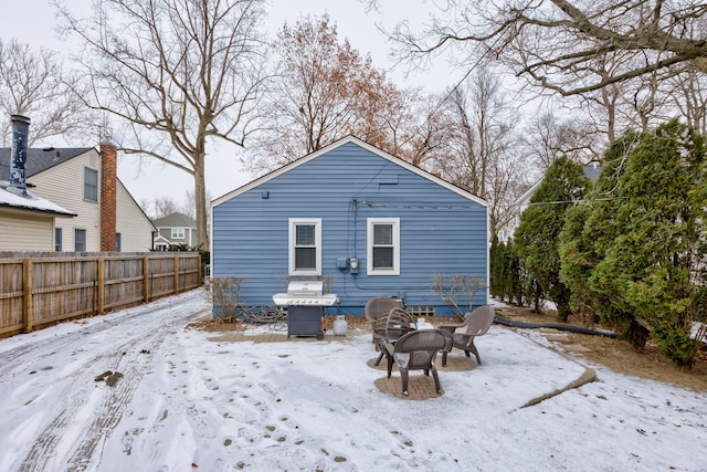 snow covered back of property with an outdoor fire pit