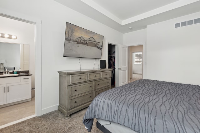 bedroom featuring ensuite bath, sink, and light carpet