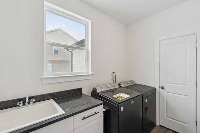 washroom featuring separate washer and dryer, sink, dark hardwood / wood-style flooring, and cabinets