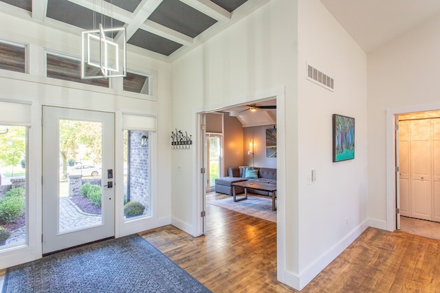 foyer entrance featuring hardwood / wood-style floors, coffered ceiling, beamed ceiling, and a high ceiling