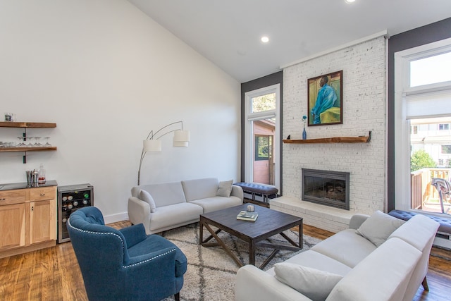 living room featuring a fireplace, hardwood / wood-style floors, high vaulted ceiling, and wine cooler