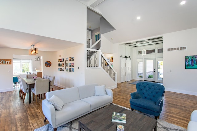 living room with dark hardwood / wood-style floors, beamed ceiling, a notable chandelier, and a barn door