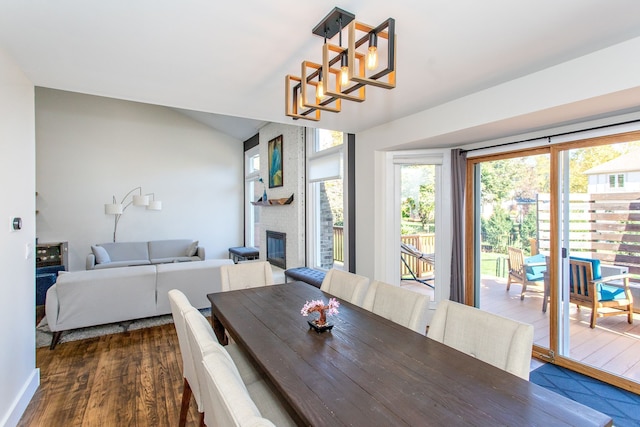 dining room featuring dark hardwood / wood-style floors, a notable chandelier, and a fireplace