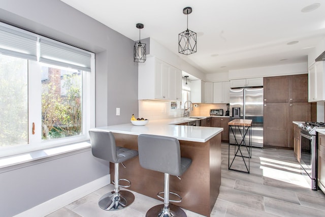 kitchen with a kitchen bar, white cabinetry, stainless steel appliances, decorative backsplash, and sink