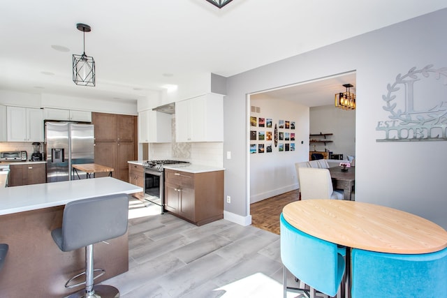 kitchen featuring white cabinets, pendant lighting, tasteful backsplash, and stainless steel appliances