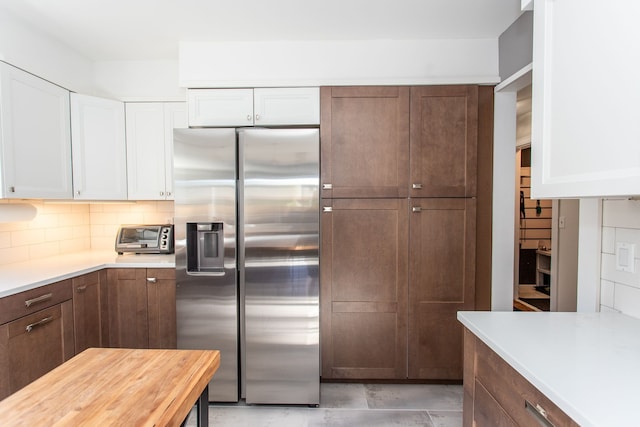 kitchen with backsplash, white cabinets, and stainless steel fridge