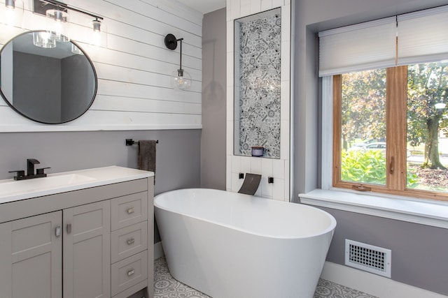 bathroom with a tub, a wealth of natural light, and vanity