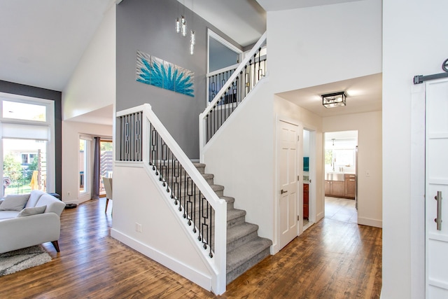 stairs featuring hardwood / wood-style flooring, a towering ceiling, and a barn door