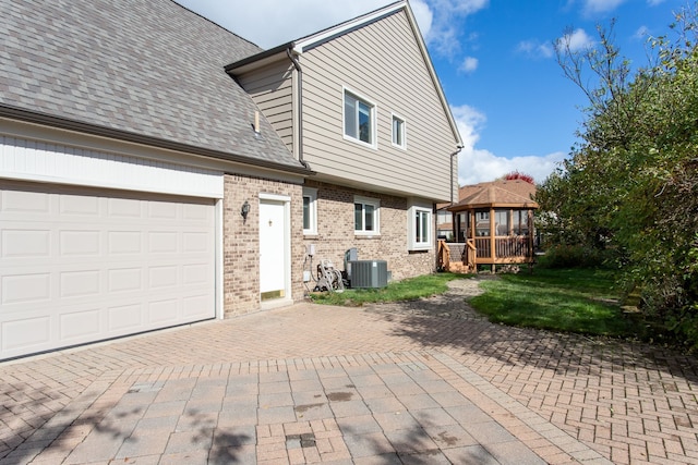 back of property with a garage, central AC unit, and a gazebo