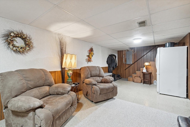 living room featuring wood walls, electric panel, and a drop ceiling