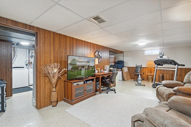 office with a drop ceiling, washer / dryer, and wooden walls