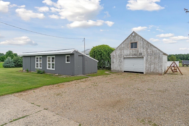 exterior space featuring a garage, a front lawn, and an outbuilding