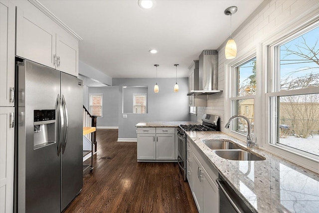 kitchen featuring decorative light fixtures, sink, stainless steel appliances, and wall chimney exhaust hood