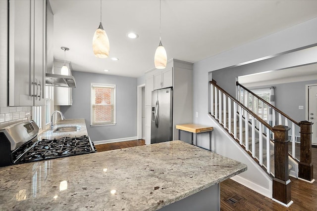 kitchen featuring light stone countertops, appliances with stainless steel finishes, sink, decorative light fixtures, and dark hardwood / wood-style floors