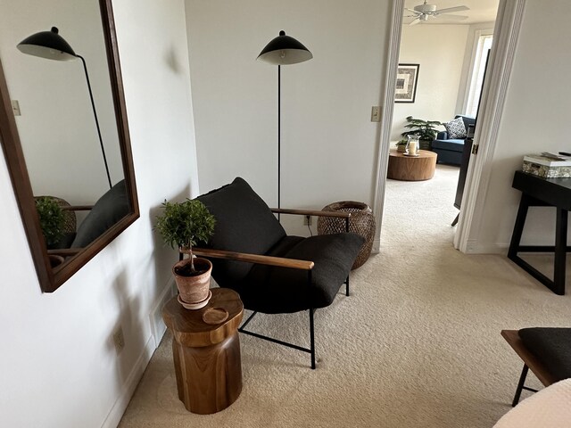 living area with carpet, baseboards, and a ceiling fan