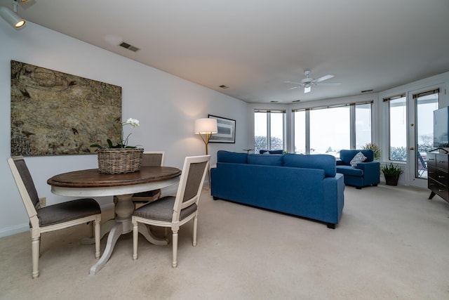 living area with ceiling fan, visible vents, and light colored carpet