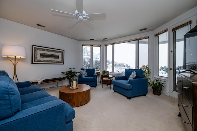 living area featuring light carpet, visible vents, and a ceiling fan