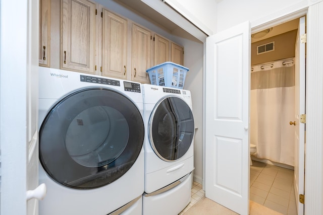 laundry area featuring light tile patterned flooring, cabinet space, visible vents, and washer and dryer