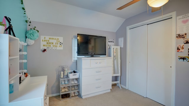 bedroom featuring ceiling fan, a closet, light carpet, and vaulted ceiling