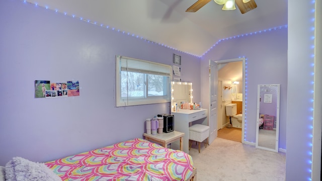 bedroom featuring light carpet, ensuite bath, vaulted ceiling, and ceiling fan