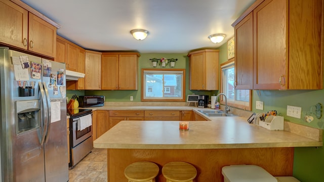 kitchen with kitchen peninsula, sink, a breakfast bar area, and stainless steel appliances