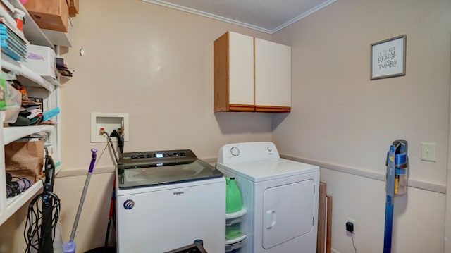 clothes washing area with washing machine and clothes dryer, cabinets, and ornamental molding