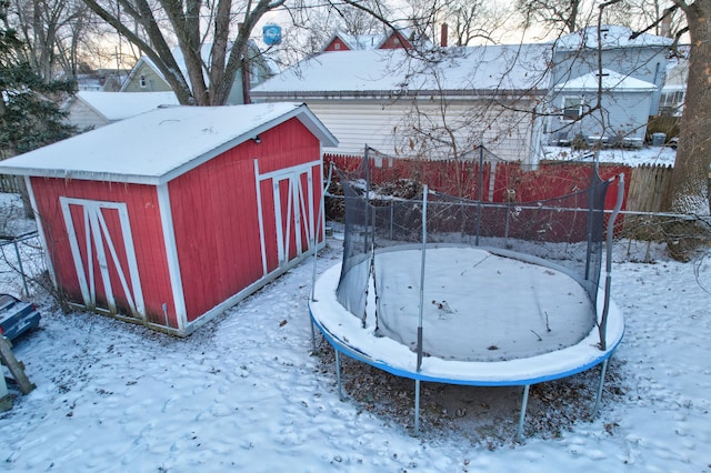 yard covered in snow featuring a storage unit and a trampoline