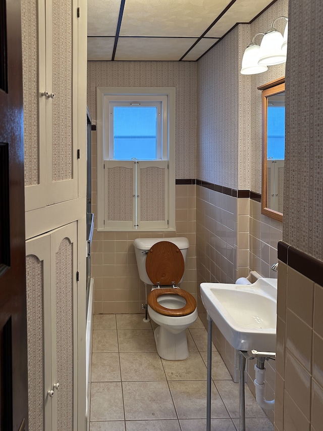 bathroom with toilet, tile walls, and tile patterned flooring