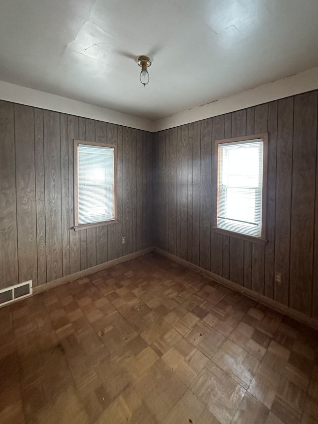 spare room with parquet flooring and wooden walls