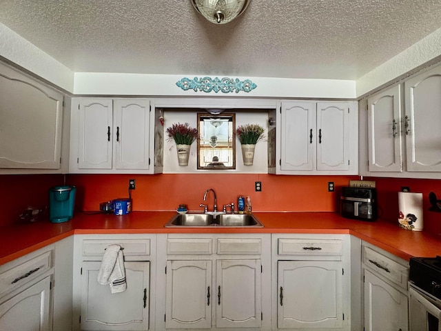 kitchen with white cabinetry, sink, a textured ceiling, and stainless steel range