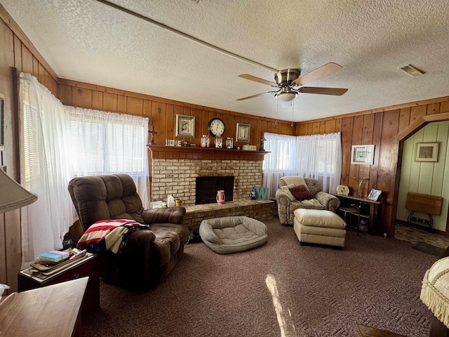 living room with ceiling fan, wood walls, plenty of natural light, and a textured ceiling